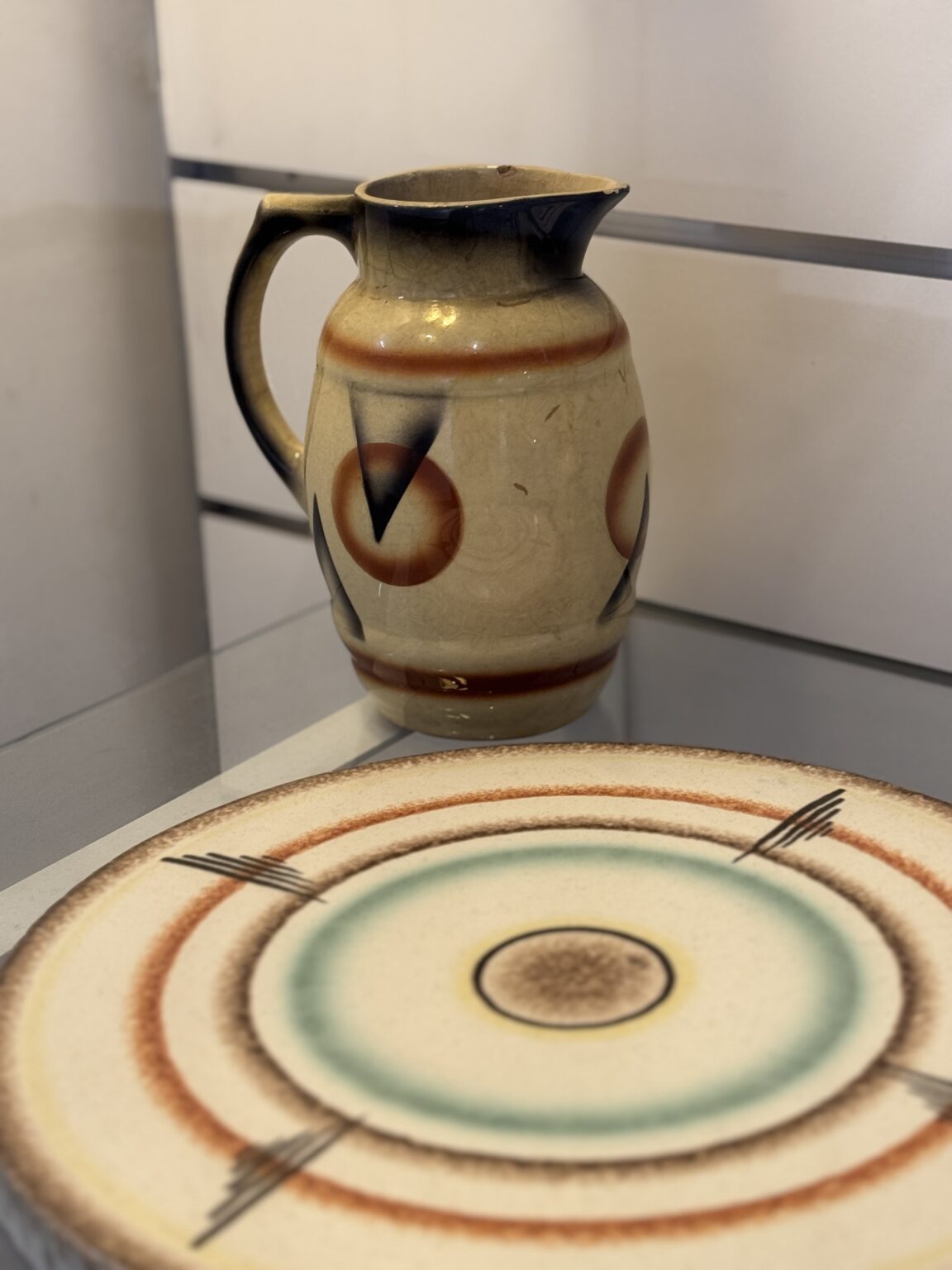 Płaska patera i dzbanek, utrzymane w odcieniach bieli, brązu i błękitu.