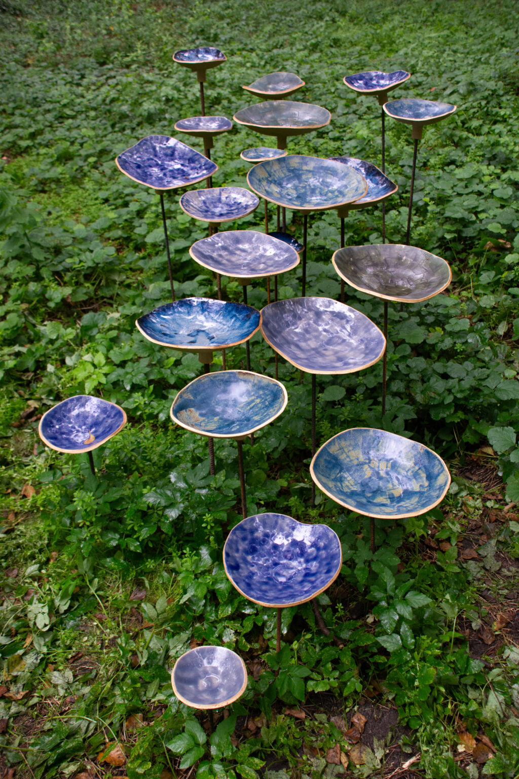 Zdjęcie przedstawiające 21 ceramicznych, niebieskich mi na trawie