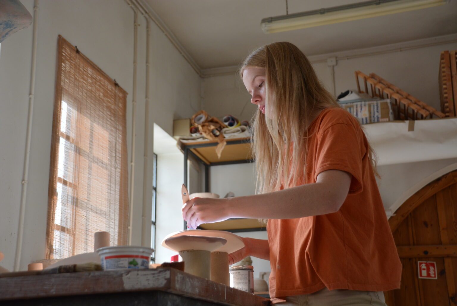 Zdjęcie przedstawia jące Gabrielę Piwar przy pracy nad ceramicznymi misami